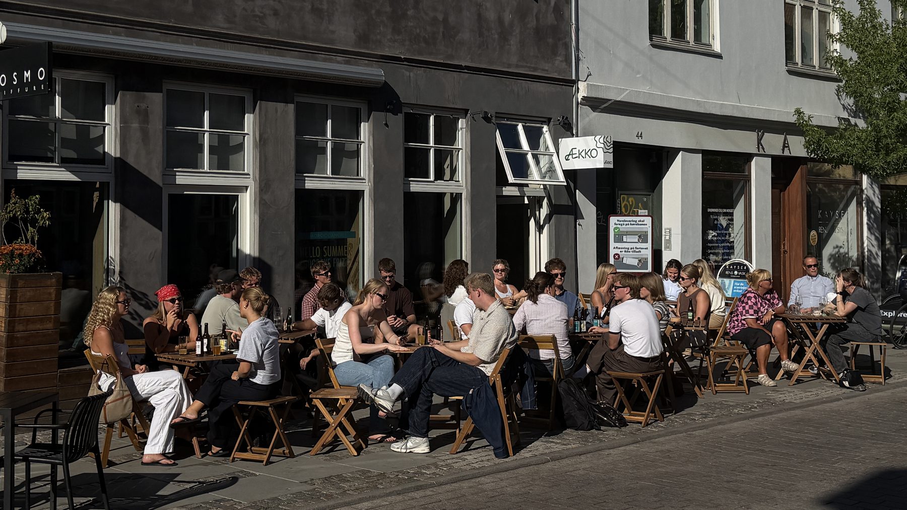 Gæster ved bordene på fortovet foran Bar Ækko på Vestergade 46 i eftermiddagssol